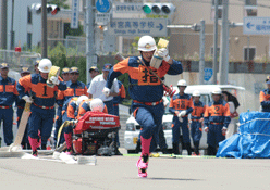 選手の方が左肩に物を担いで走っている写真