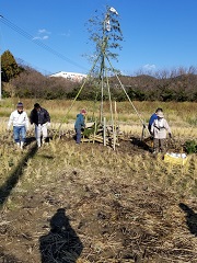 広い田畑に竹を組んでやぐらを作り、どんど焼きの準備をしている方々の写真