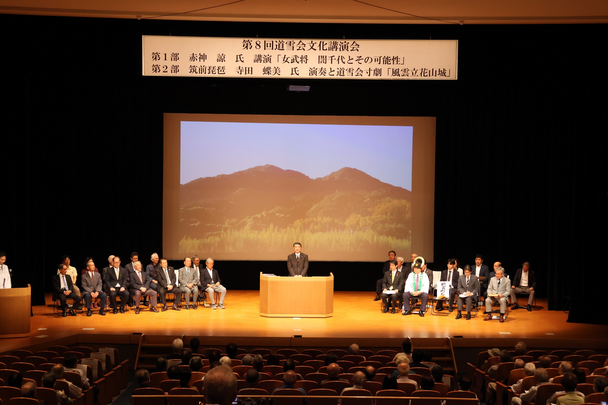 演台に立ち、マイクを通して挨拶をしている桐島町長の写真