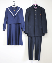 紺色の女子生徒用のセーラー服と、黒の男子生徒用の学ランがハンガーにかけられている写真