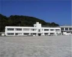 白色の外観で2階建ての相島小学校と広々とした校庭が広がっている相島小学校の外観写真