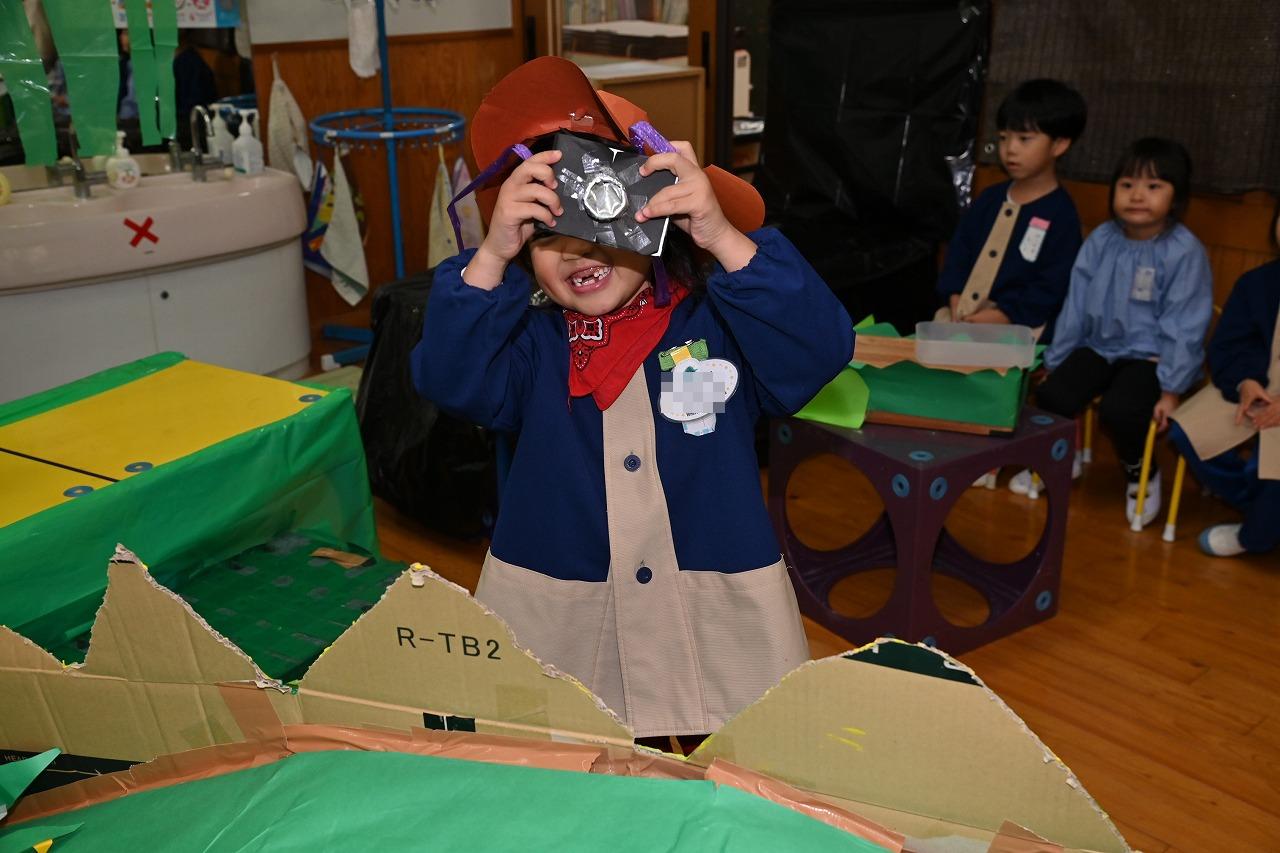 年長女児が、作ったカメラを持って、写真を撮るポーズをとっている