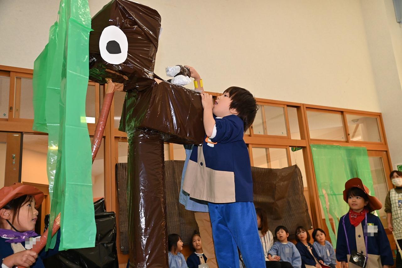 男児が、恐竜にの口に、作り物のえさを食べさせている様子