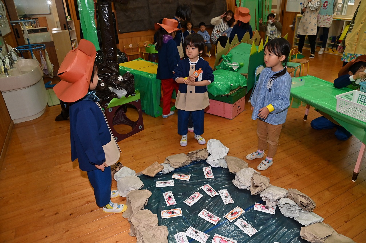 手作りの池に魚が置いてあり、その周りに園児3人が経っている様子