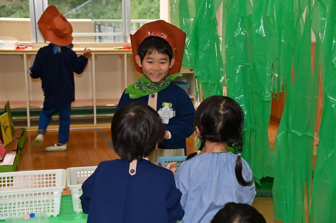 テーブル越しに、年長児が笑顔で、年少年中児2名を迎えている様子