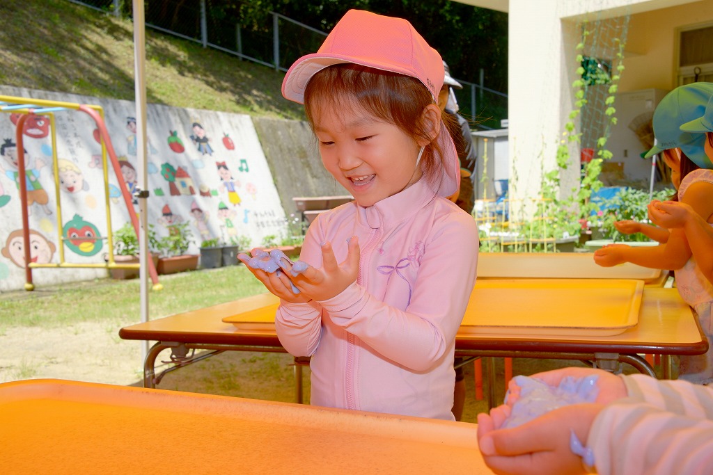 女児が小麦粉粘土を手にのせてもらって、嬉しそうに見つめている様子