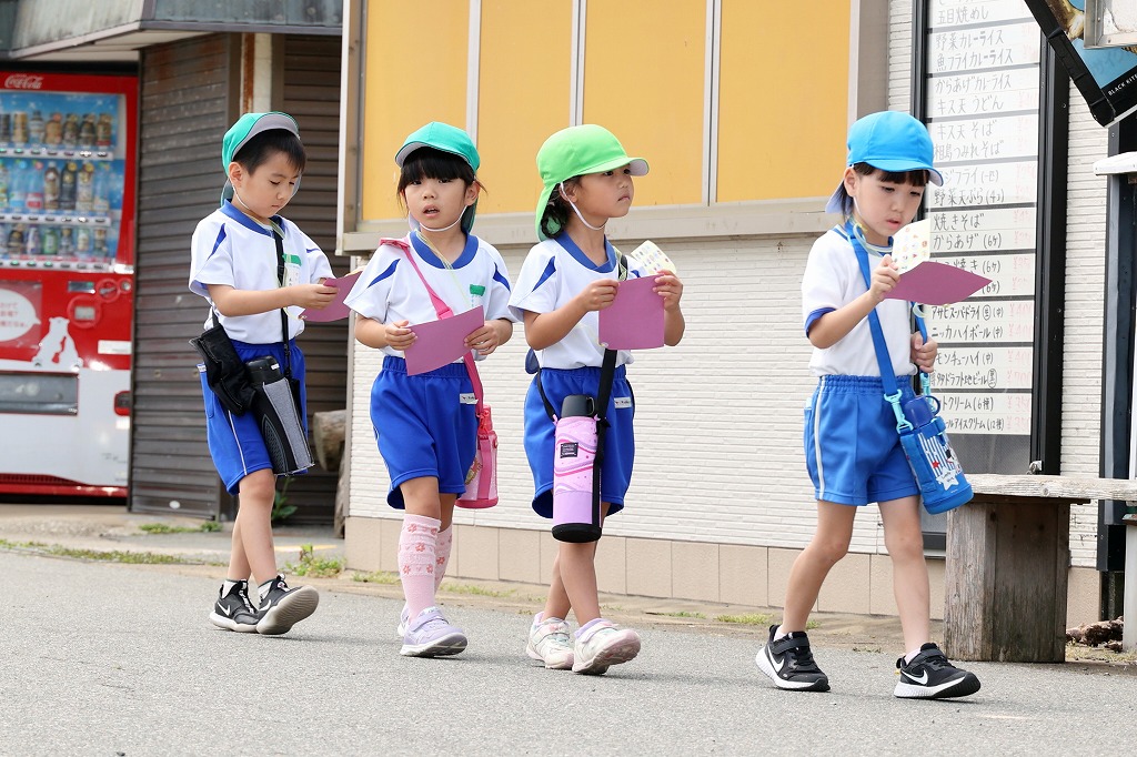 4名の園児が探検カードを持って相島を探検している様子