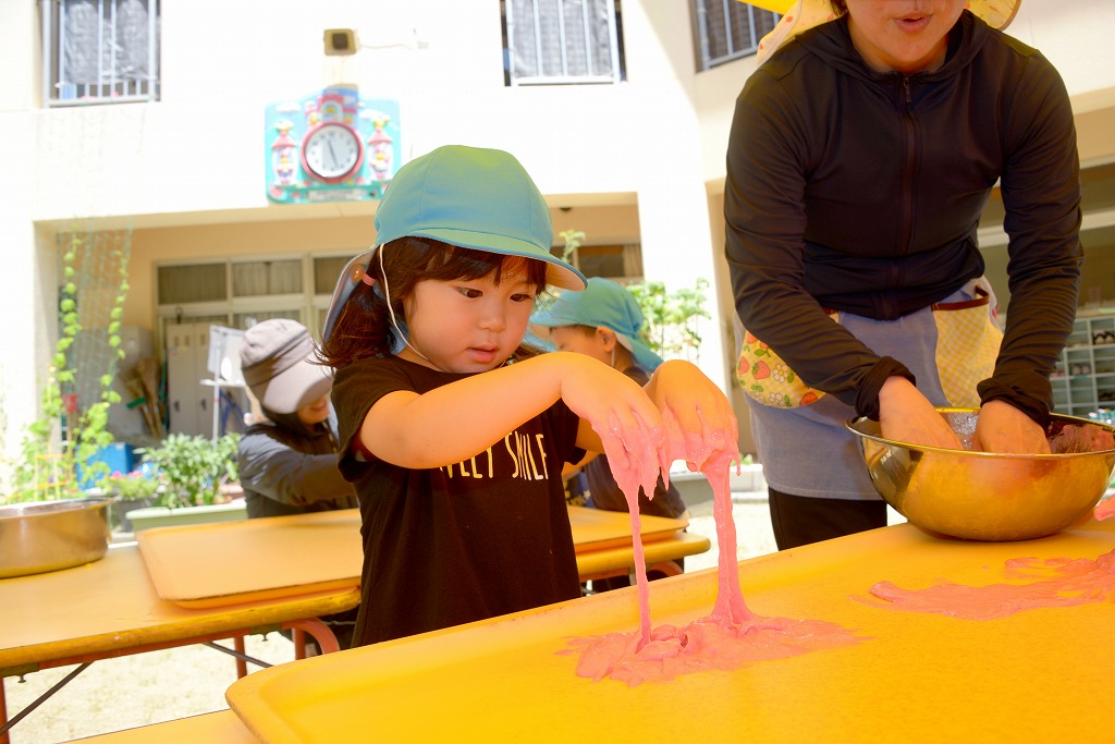 女児が小麦粉粘土を両手に付け、ドローっと垂れている様子を見つめている