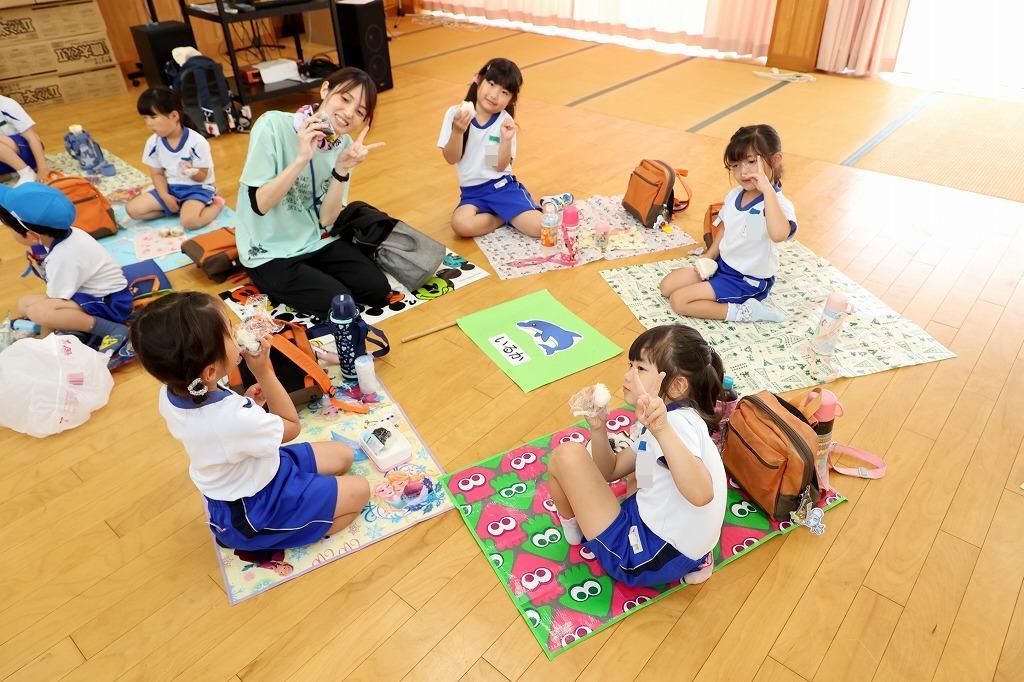 相島ふれあい館で、先生と園児たちが輪になって、おにぎりを食べている様子