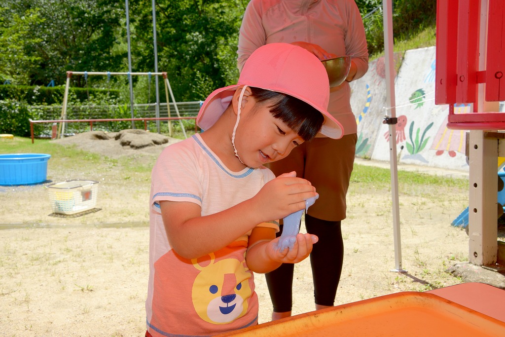男児が小麦粉粘土を手のひらに載せ、右手から左手にとろーっと垂らして喜んでいる様子