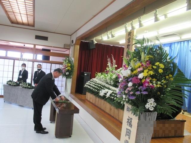 たくさんの花が飾られた戦没者の祭壇の前に町長が立ち、献花をしている写真