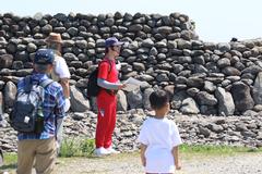 上下赤い服を着た中学生がガイドをしている相島ウォーキングの様子の写真