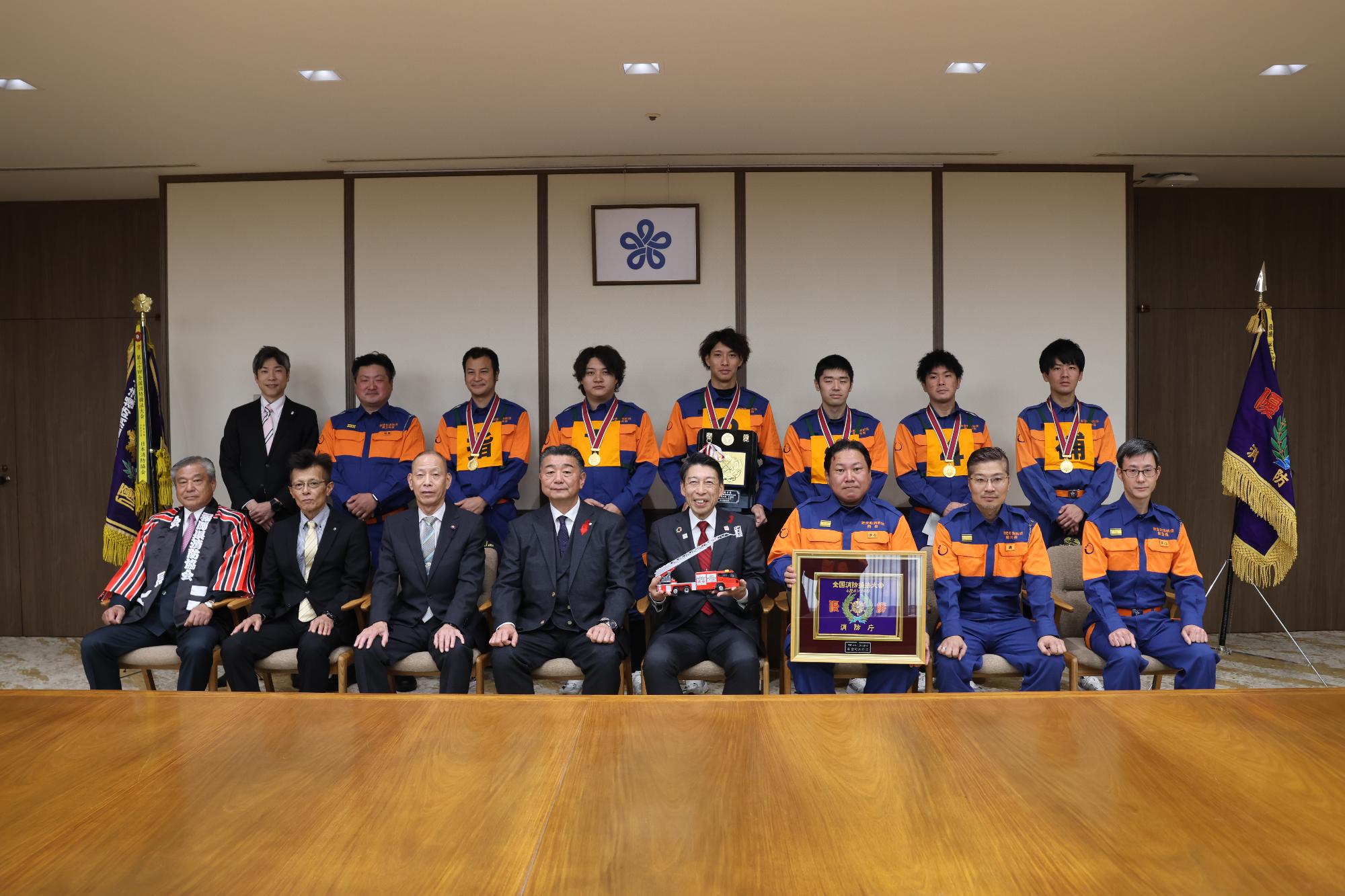 福岡県知事と町長らが消防団員と記念撮影をしている写真