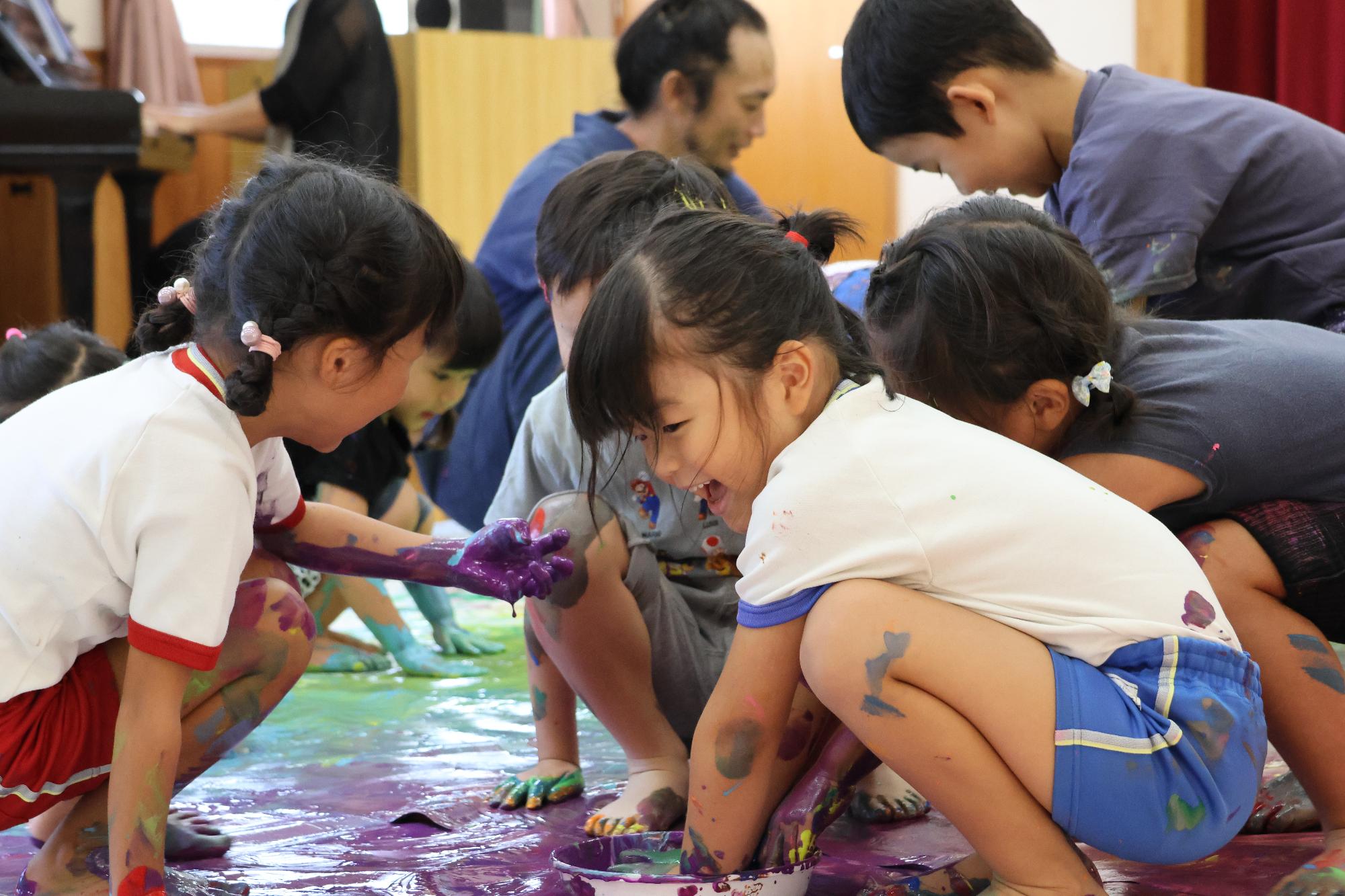 女児二人が笑顔で絵具遊びをしている様子