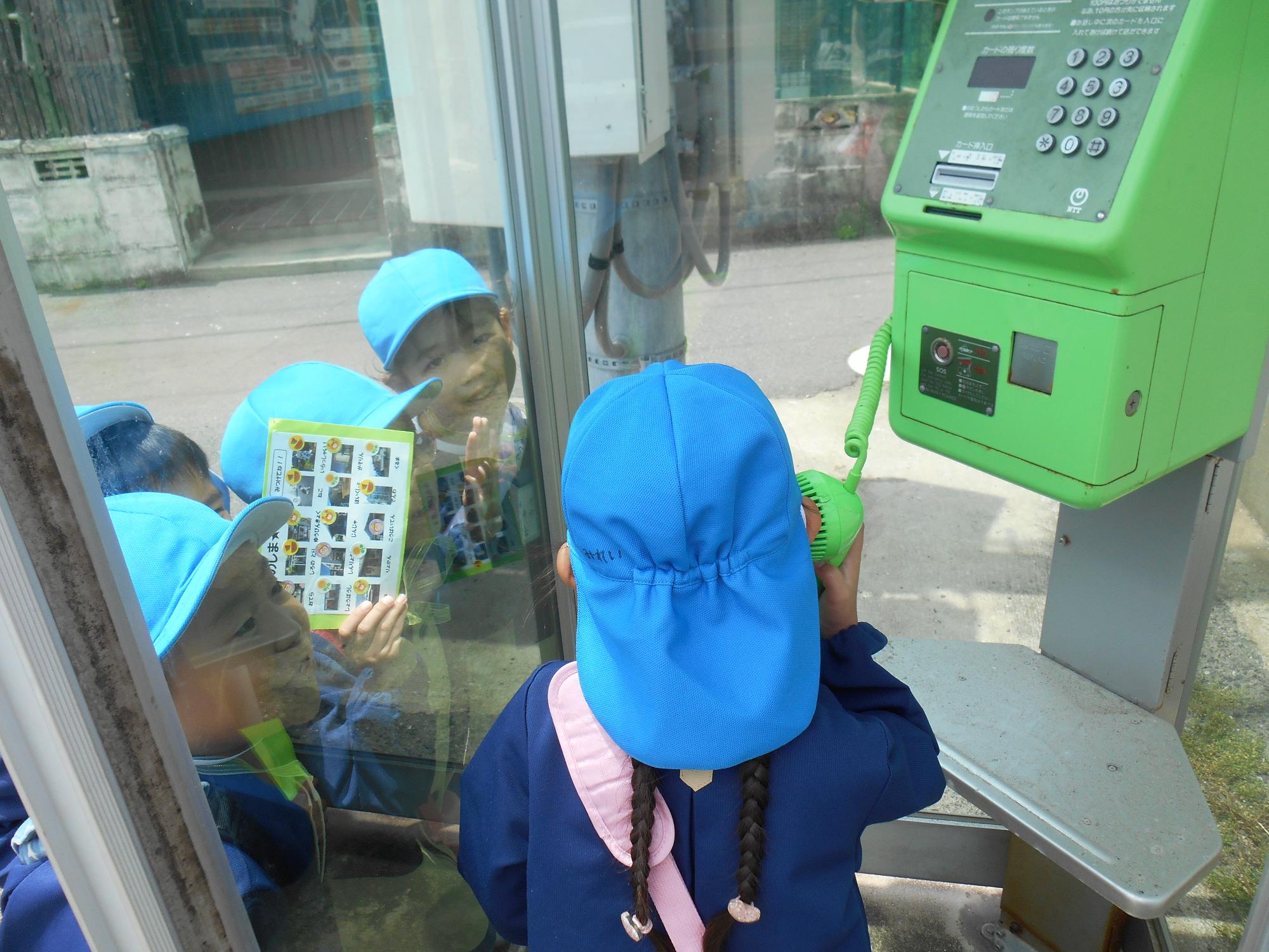 公衆電話から幼稚園に電話をかける年長さん