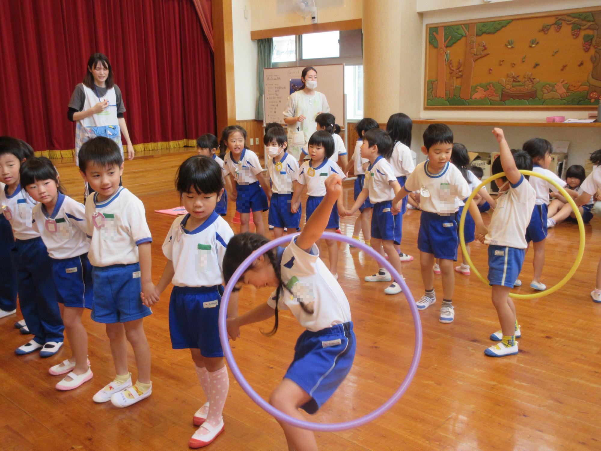 年長児たちがグループ対抗でフープ送りゲームをしている様子