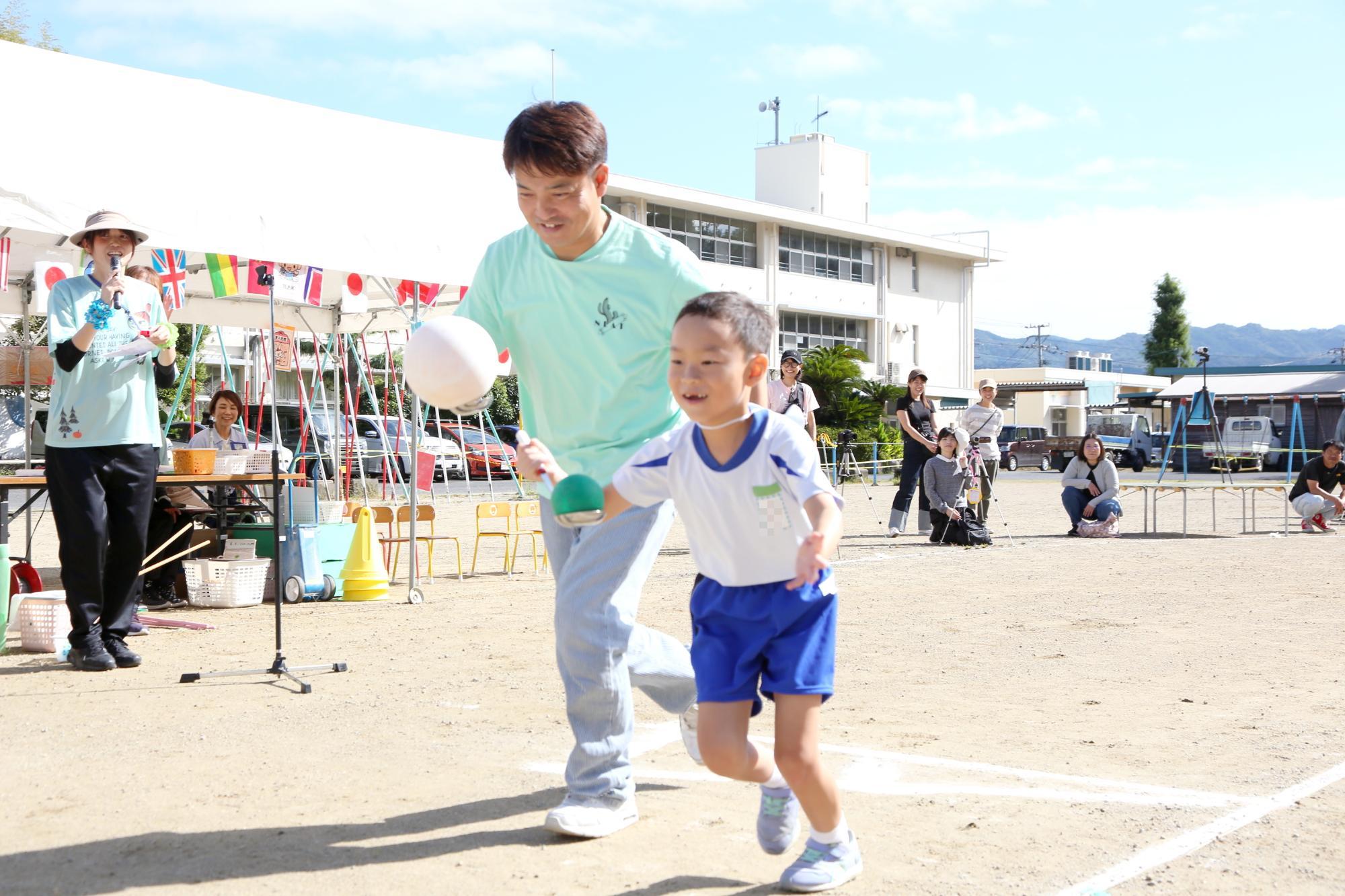 男児1名とその父親がお玉にボールを載せて、競争している様子