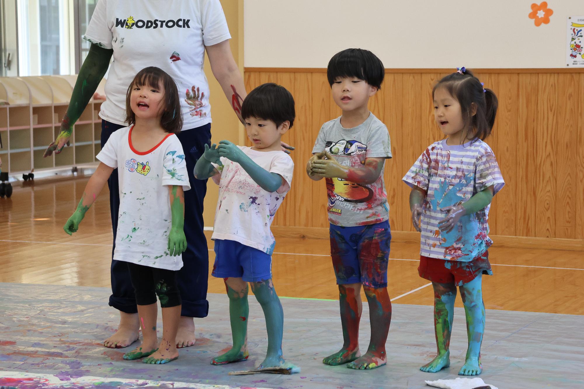 全身絵具だらけの年中児4名が笑顔で写っている