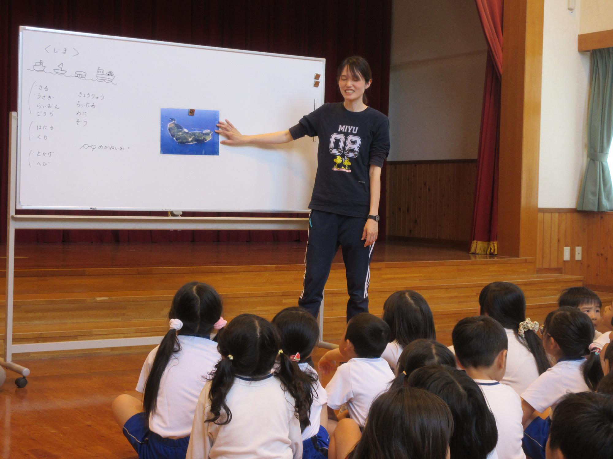 先生が指さした相島の写真を園児たちがみている様子