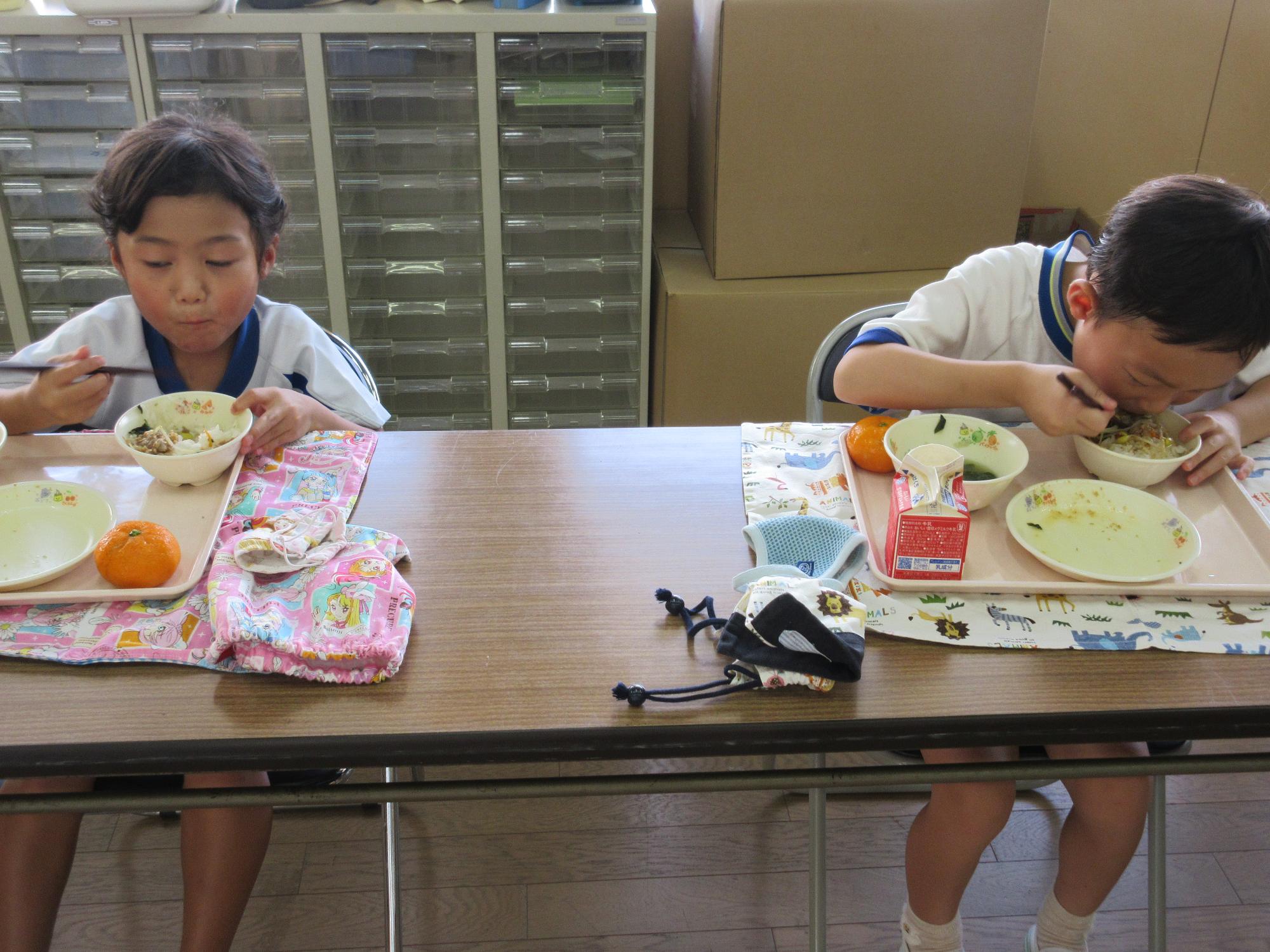 給食をおいしそうに食べる2人の年長さんの様子