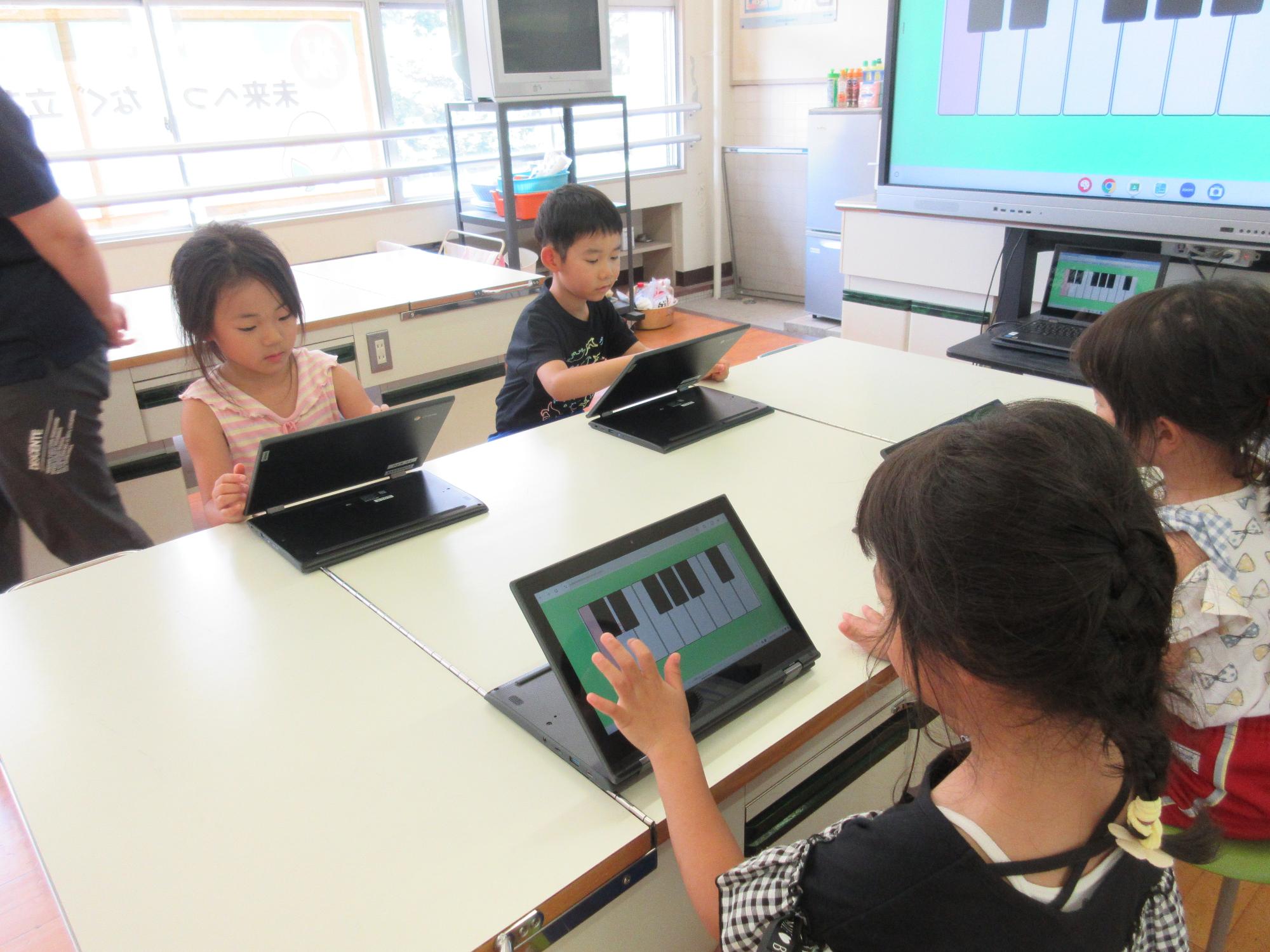 タブレットの画面に表示されているピアノの鍵盤を触る年長さん
