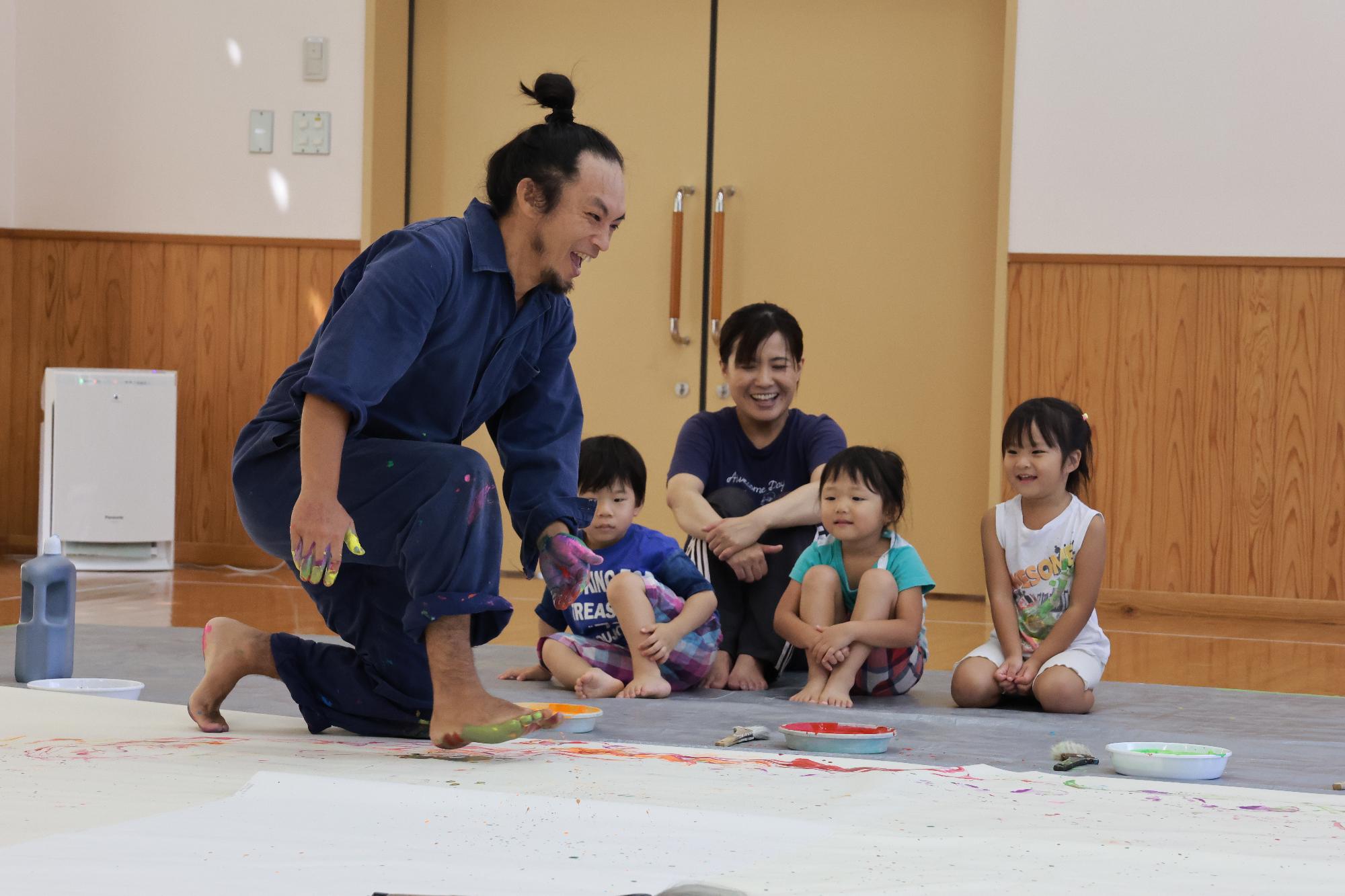 三四郎さんが大きな紙の上で踊りながら描く様子