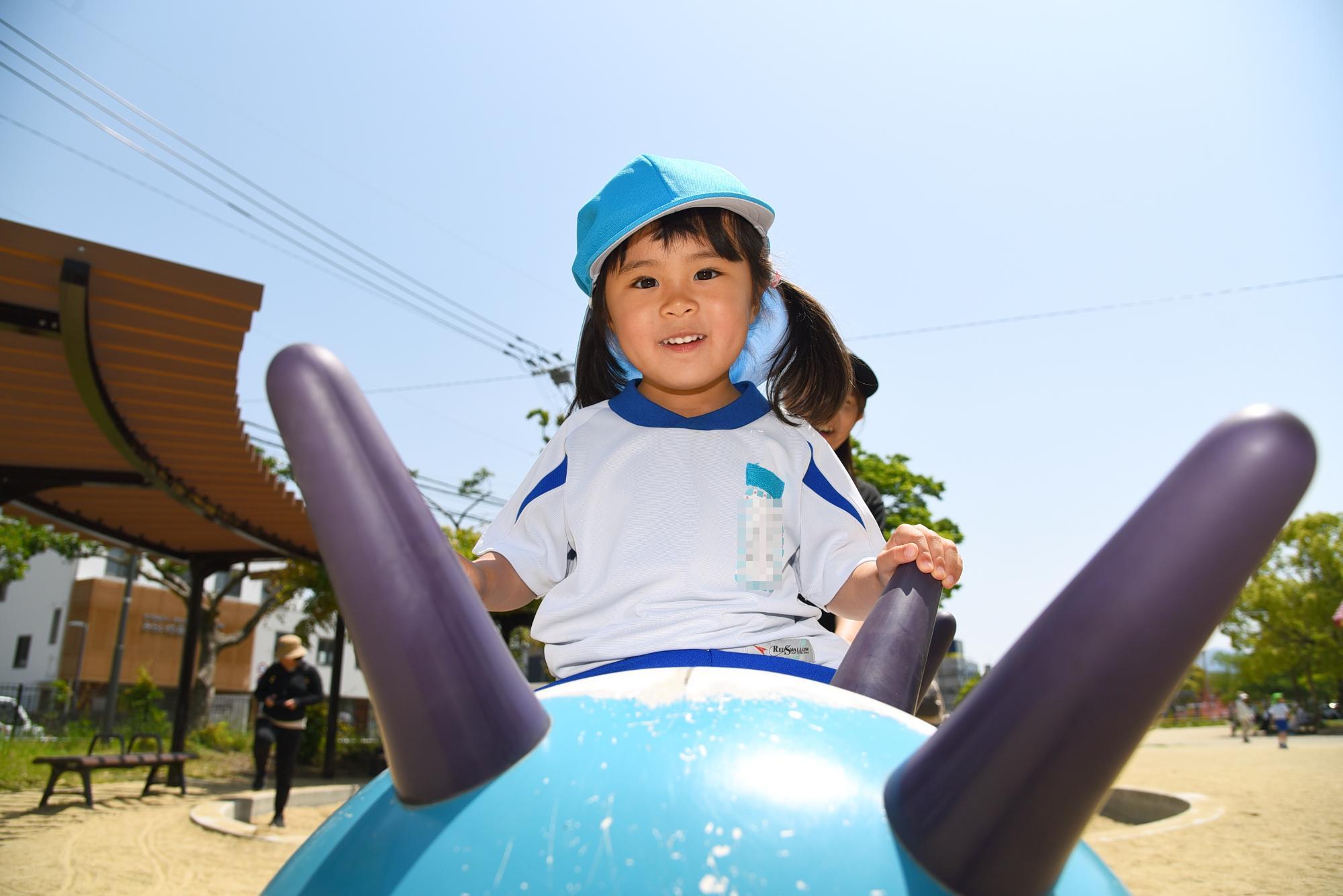 女児が遊具から、ひょっこり笑顔をのぞかせている様子