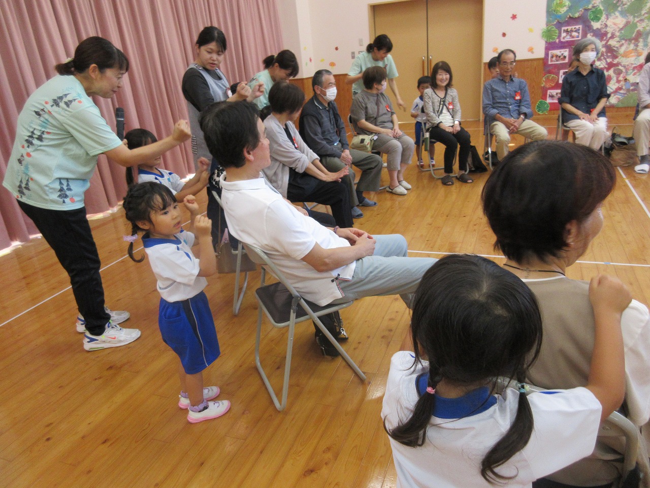 園児がおじいちゃんおばあちゃんの方をたたいている様子