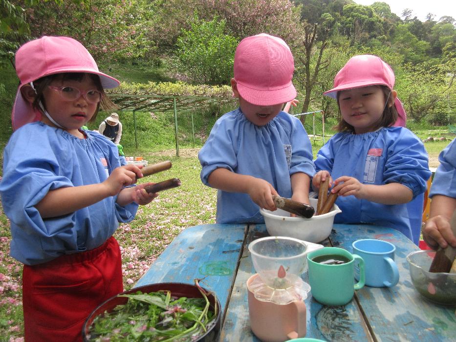 年中児3名が草花を使って遊んでいる様子