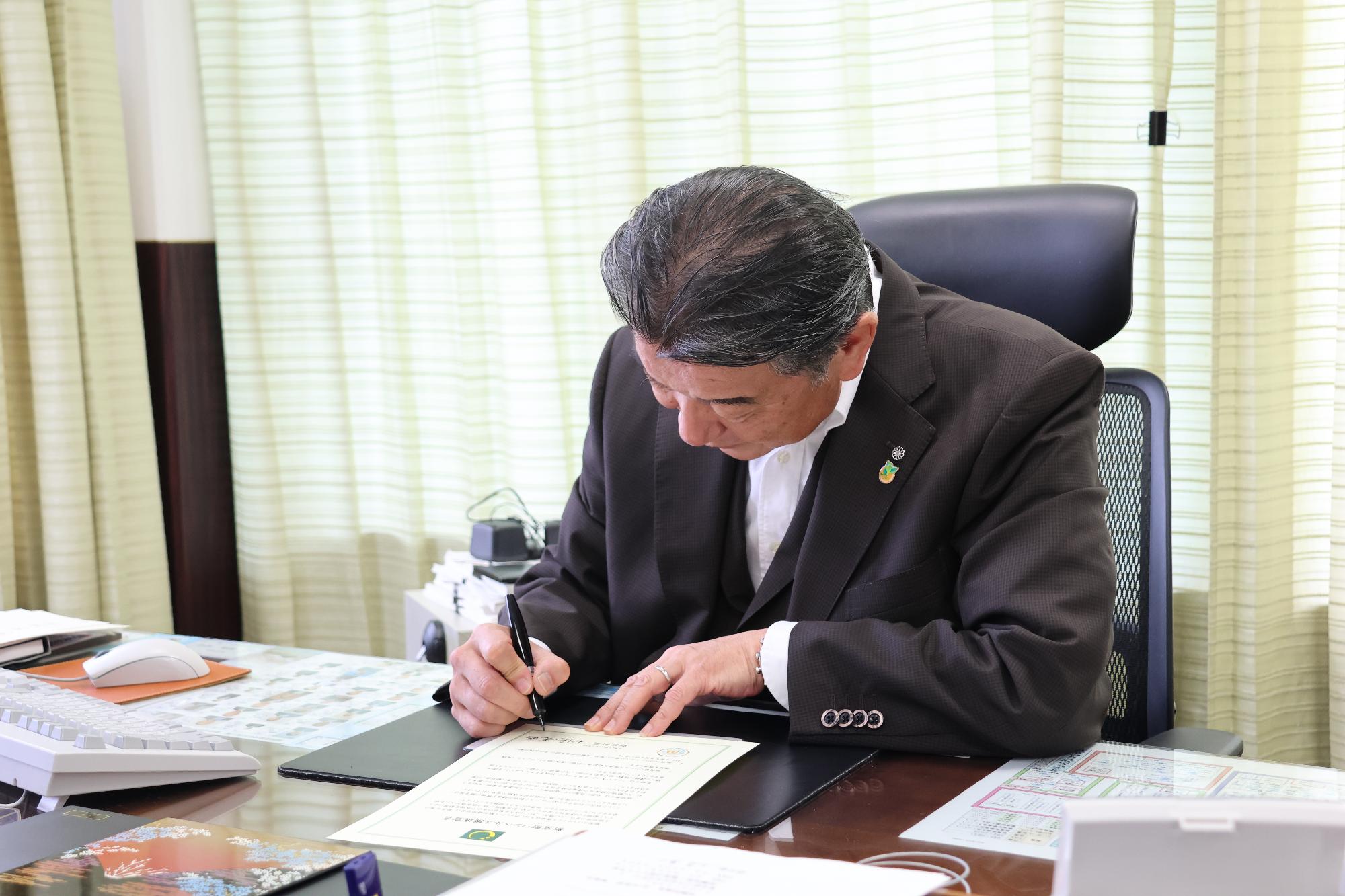 桐島町長が新宮町ワンヘルス推進宣言文に署名している写真