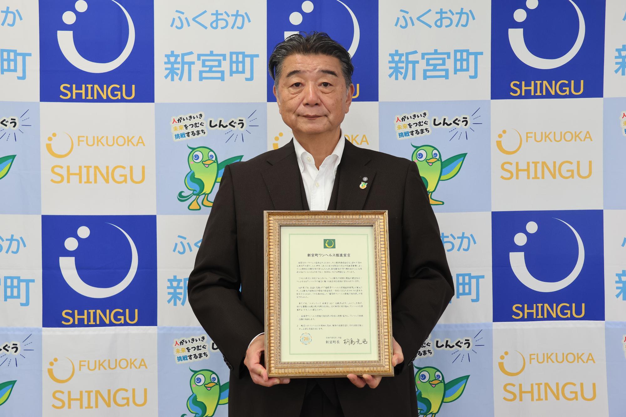 桐島町長が額縁に入った新宮町ワンヘルス推進宣言文を持っている写真