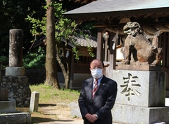 神社の前にある狛犬の前に立つ町長の写真