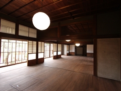 和室の中央に丸い電灯が飾られた広い室内を写した写真