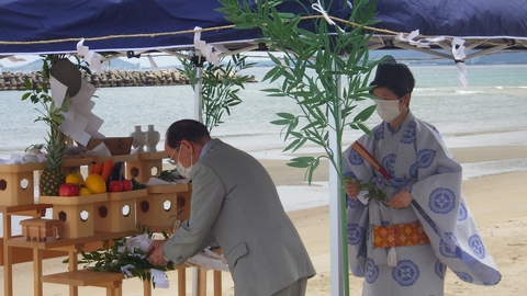 町長が飾り棚の前に立ち、玉串を添えている写真